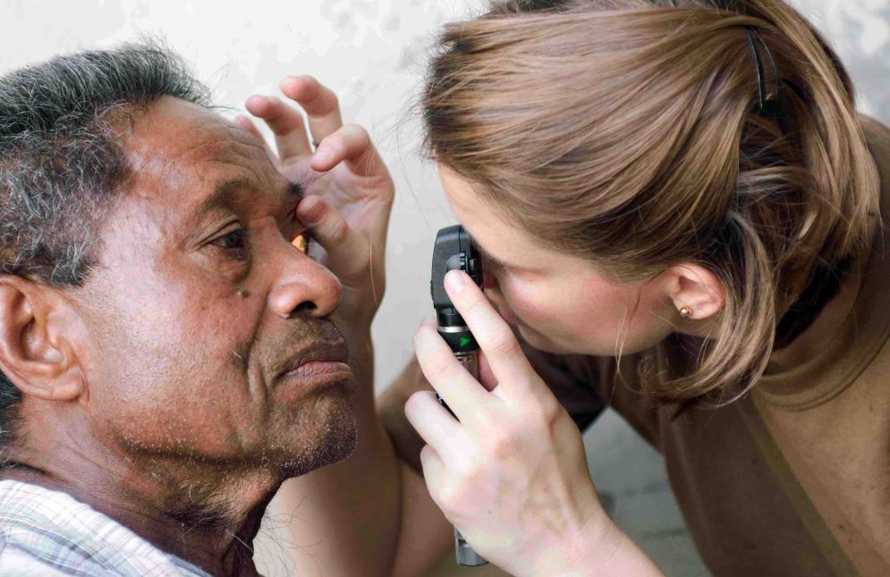 girl giving an eye checkup to an old man